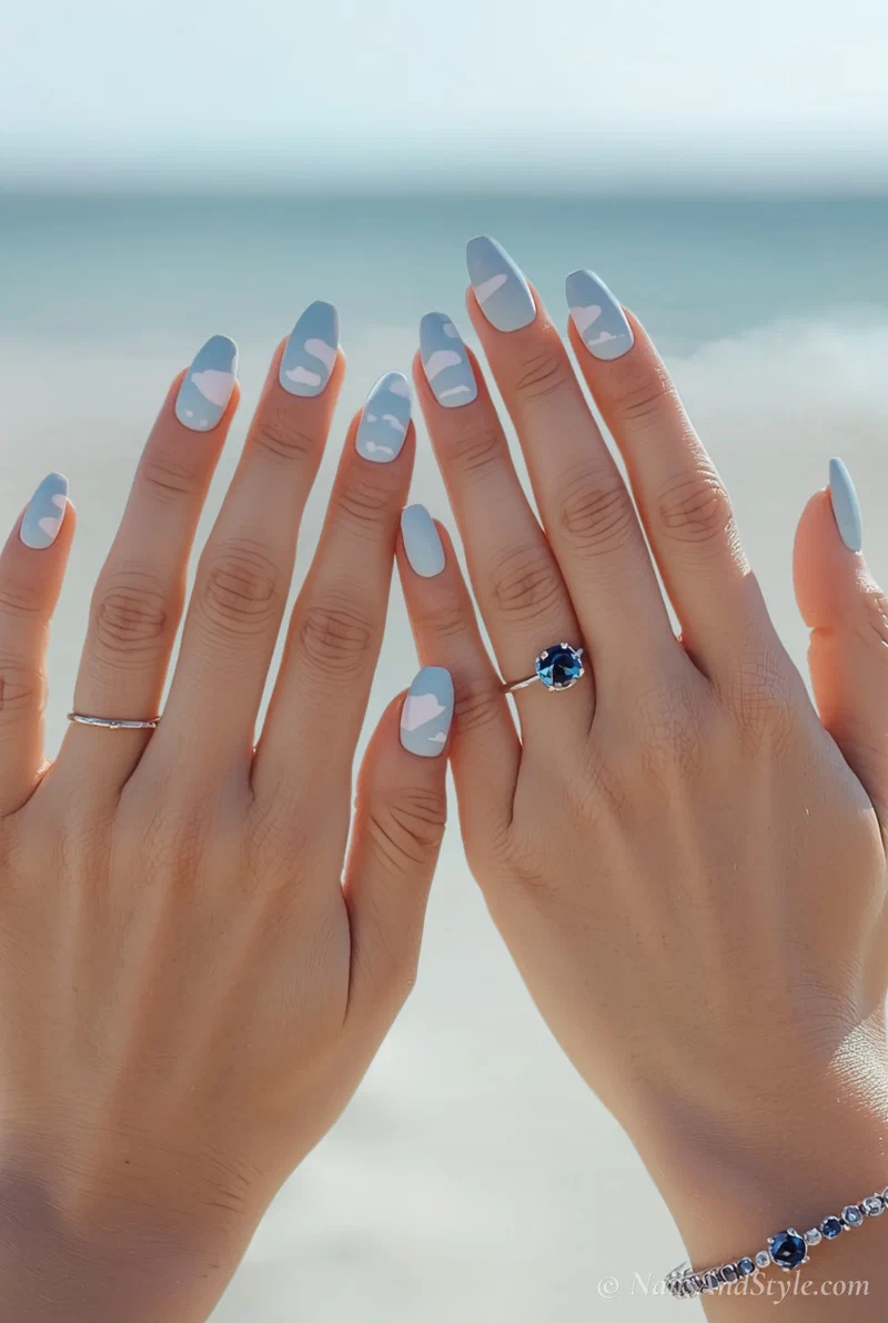 Baby blue acrylic nails with painted white cloud designs