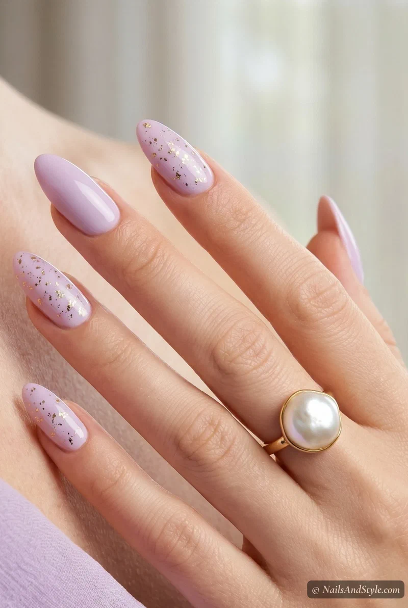 Soft lilac acrylic nails with scattered gold foil accents