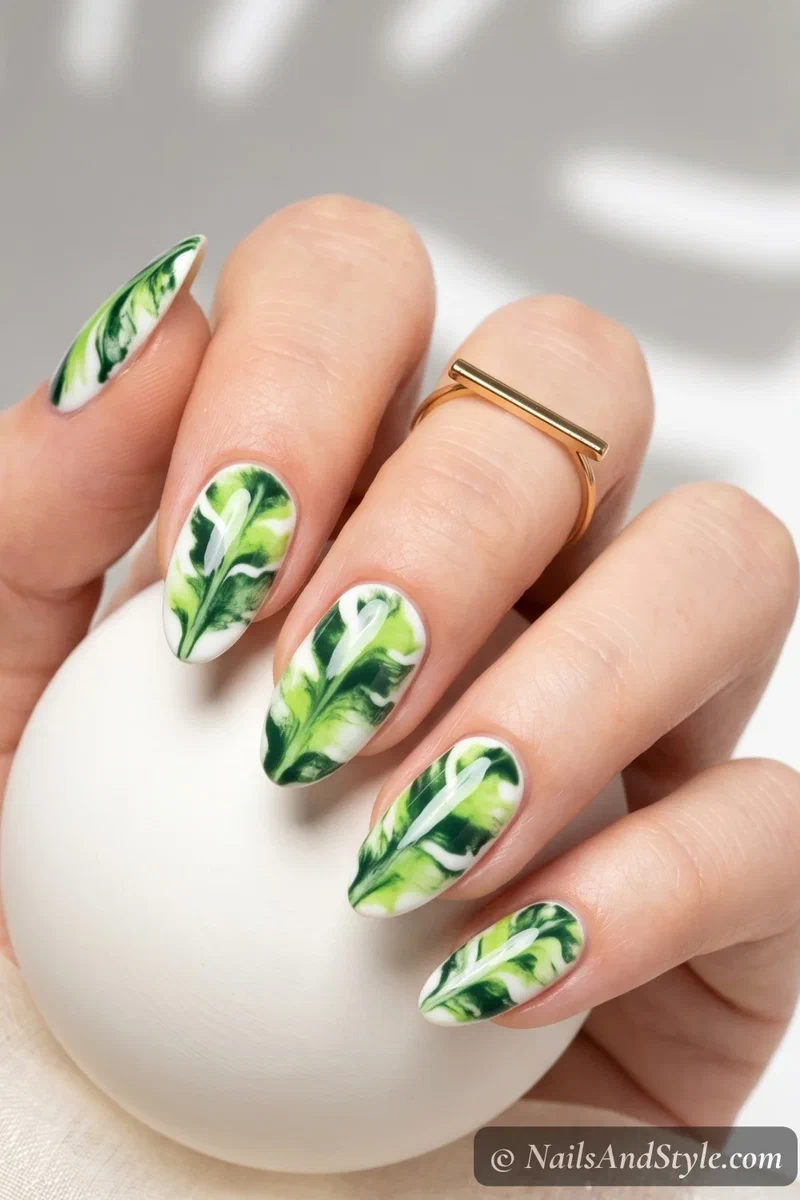 Green and lime marble nails resembling banana leaf texture on white base
