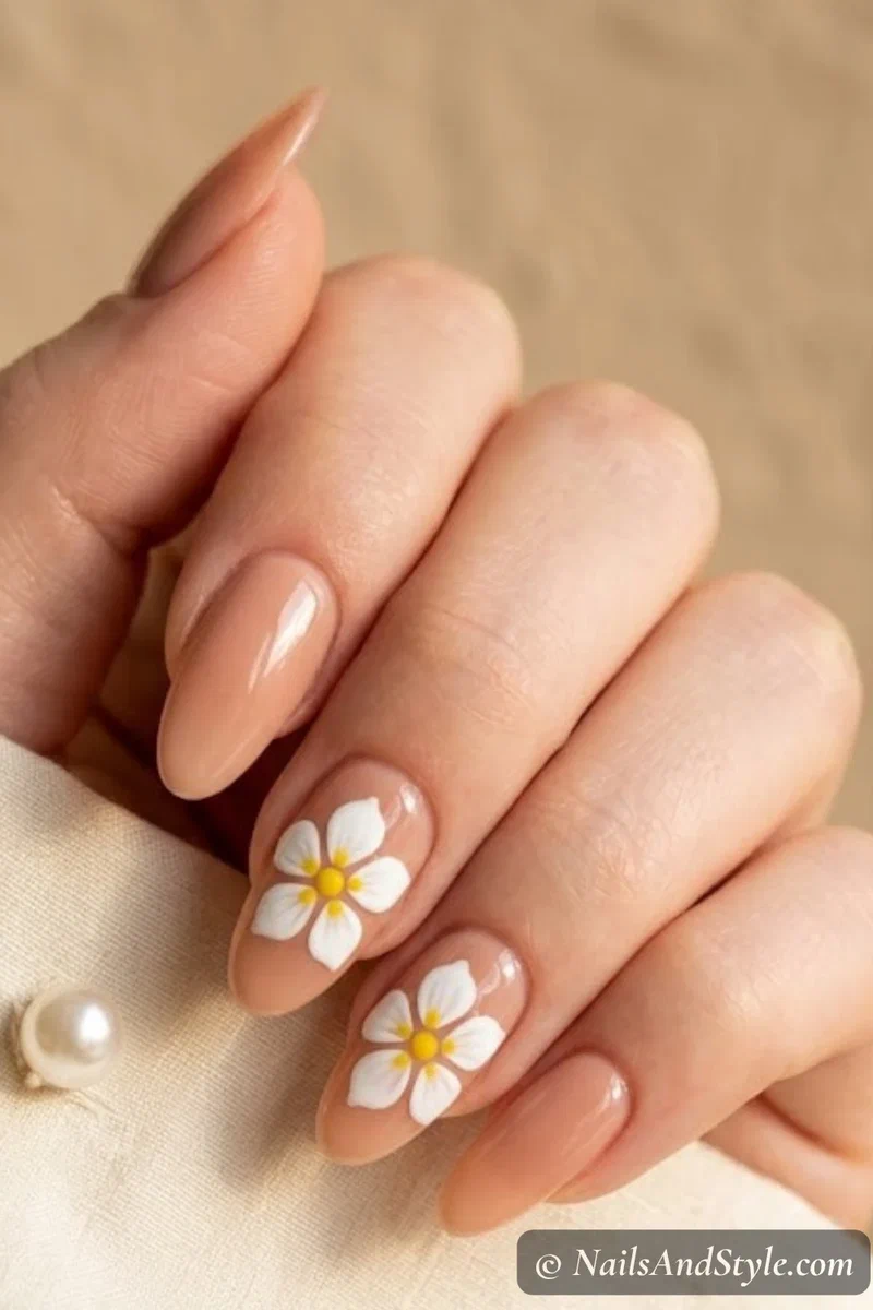 Nude base nails with white plumeria flower accent art using dotting tool