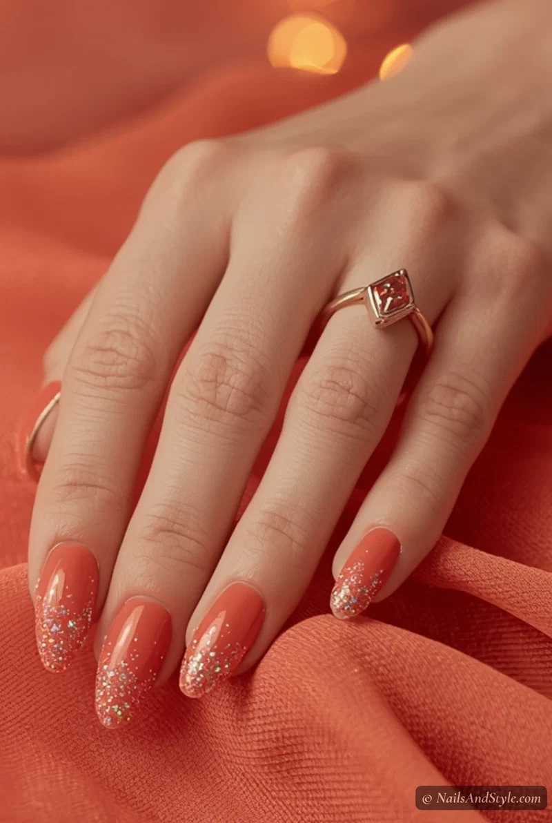 Coral nails with iridescent glitter fade toward tips on almond nails