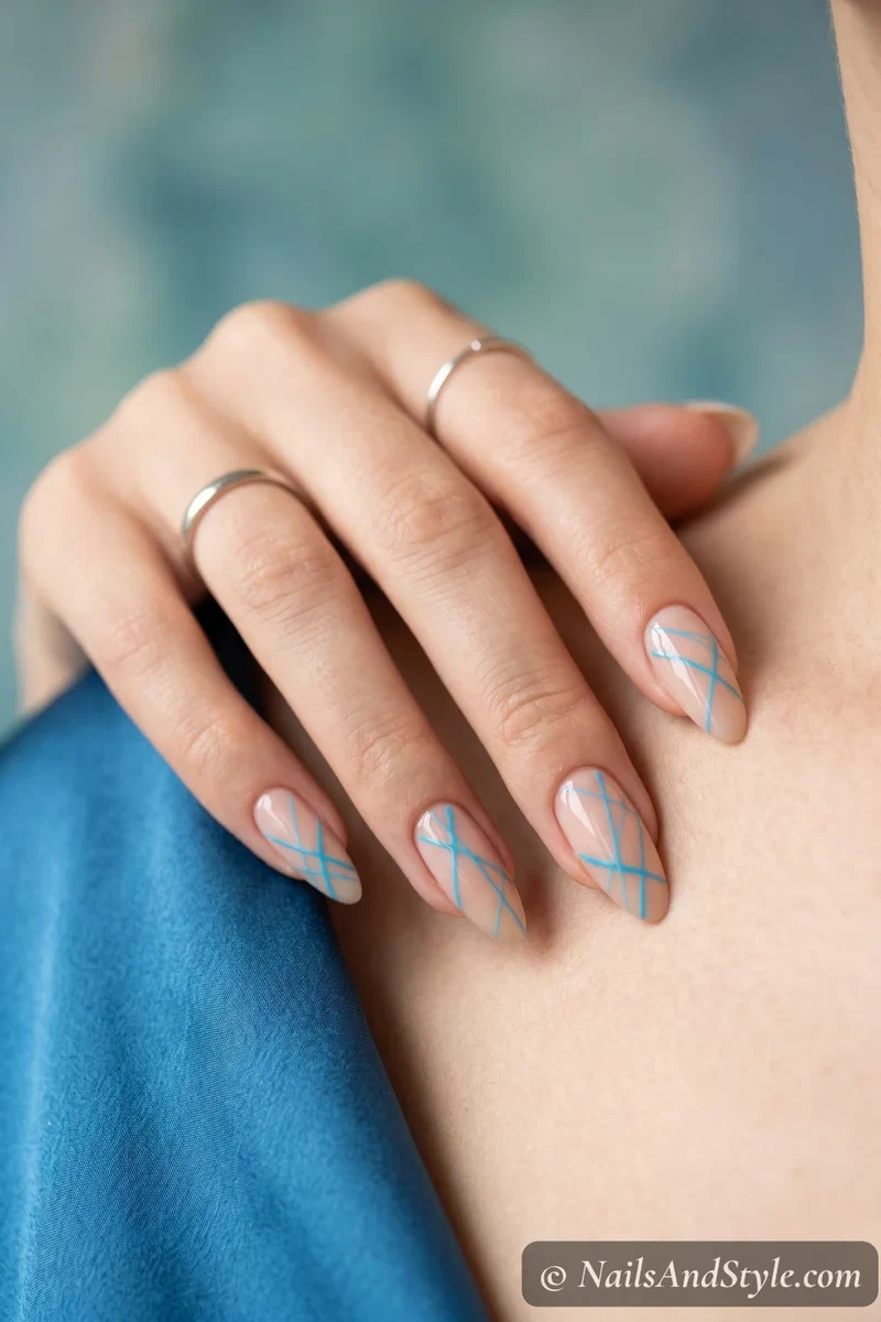 Nude base nails with random thin cyan abstract lines in modern pattern