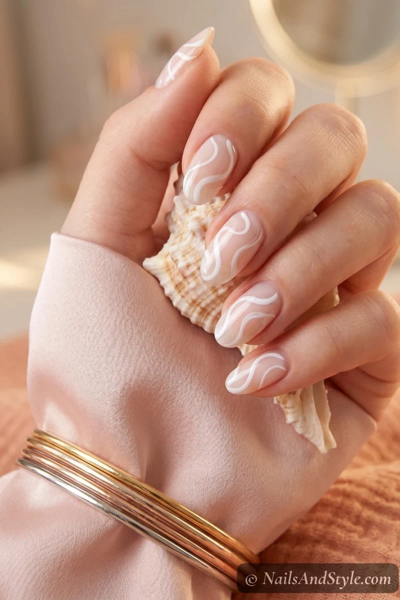White swirl nail art with freehand curves on milky nude base on medium round nails